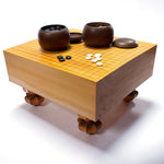 Honkaya itame goban (go board) with two opened kitani goke on top. The left one has river slate goishi in it and the right one has clamshell goishi. 